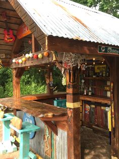 an outdoor bar with lots of items hanging from it's roof and some trees in the background