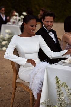 a man and woman sitting at a table with white cloths on it, smiling