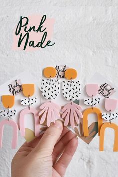 a person holding up some pink and orange paper cut outs with the words pink made on them