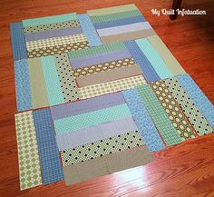 a close up of a patchwork quilt on the floor with wood floors in the background