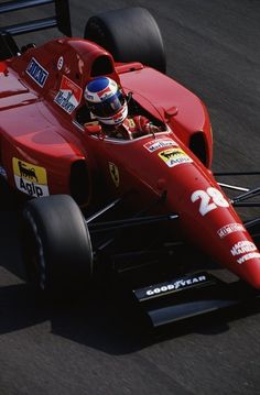 a man driving a red race car on a track