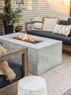 a concrete fire pit sitting on top of a patio next to a couch and table