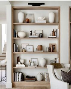 a living room filled with lots of furniture and shelves covered in vases on top of them