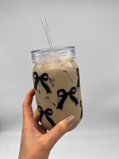 a hand holding a drink with black bows on it and a straw in the cup