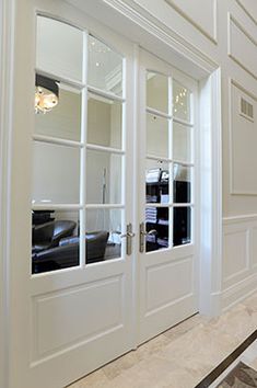 the interior of a house with white walls and doors that have glass panes on them