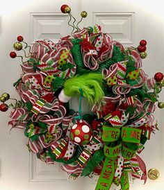 The Grinch Strikes! Adding Some Sass to this Awesome Handmade Wreath! Picture this: a seriously cool mesh and ribbon wreath, all decked out with vibrant colors, hanging out on a door or wall. But wait for it... who's sneaking in? The Grinch! That cheeky green guy just can't resist adding his own touch to this already awesome wreath!This wreath? It's a total dazzler— 36 inches of holiday cheer, filled with ribbons and ornaments in the raddest shades of red, green, and white. Whoville Christmas Wreath, Present Wreath, Grinch Themed Christmas Wreath, Grinch Reef, Christmas Wreath Decorating Contest, Christmas Wreaths Grinch, Fun Christmas Wreath Ideas, Christmas Grinch Decor Ideas, Grinch Mesh Wreath