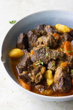 a bowl filled with meat and potatoes on top of a table