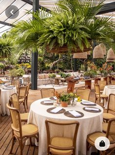 an outdoor dining area with tables, chairs and potted plants on the table top