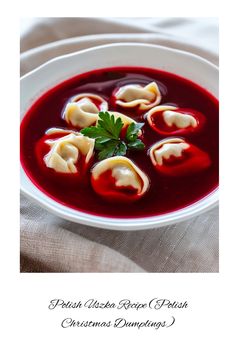 a white bowl filled with red soup and dumplings on top of a table cloth