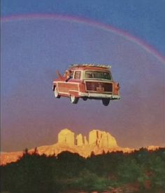 an old car is flying in the air with a rainbow behind it