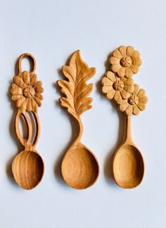 three wooden spoons with flowers and leaves on them