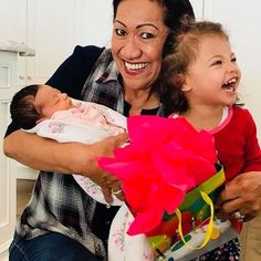 a woman holding a baby and smiling at the camera with her gift wrapped in pink