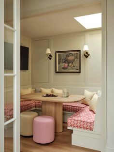 a room with a table, bench and ottomans in the corner next to it