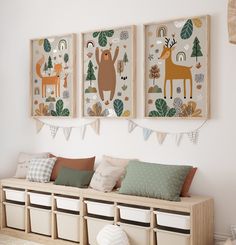 three framed pictures hang on the wall above a bench with storage bins underneath it