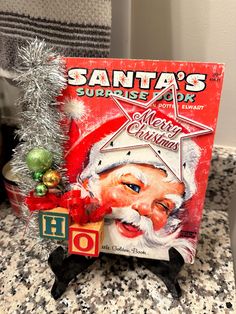 a santa's surprise book sitting on top of a counter next to a christmas tree