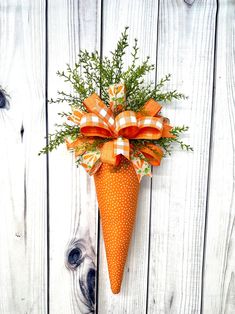 an orange and white polka dot cone with greenery in it hanging on a wooden wall