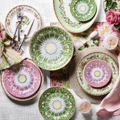 a table topped with lots of plates covered in different colors and designs on top of each other