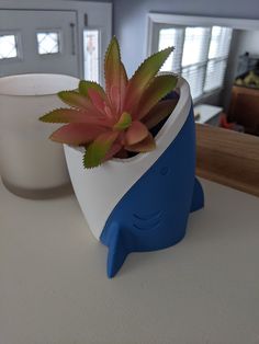 a blue and white container with a plant in it sitting on a counter next to a cup