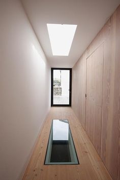 an empty hallway with a skylight and wooden walls on either side, leading to the bedroom