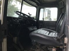 the interior of an old truck with black leather seats and steering wheel rests on the floor