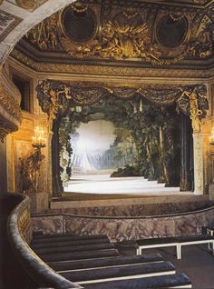 an ornately decorated stage with chandeliers and benches in front of the stage