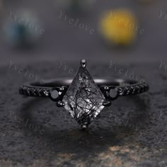 a white diamond ring sitting on top of a black stone surface with the words love in it