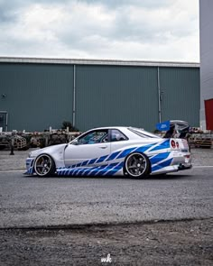 a white car with blue stripes parked in front of a building on the side of the road