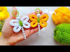 two crocheted butterflies are being held in front of balls of yarn and flowers