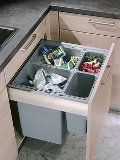 an open trash bin in the middle of a kitchen counter with food and drinks inside