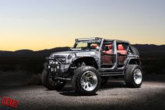 a jeep with red seats is parked in the middle of an open field at sunset