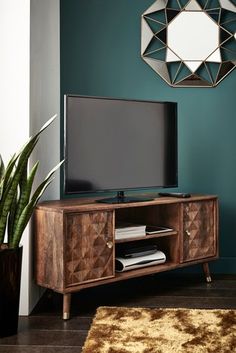 a flat screen tv sitting on top of a wooden entertainment center next to a potted plant