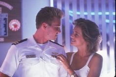 a man and woman in uniform standing next to each other looking into each other's eyes