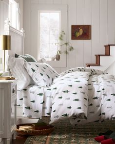 a bed with white sheets and green trees on it in a room next to stairs