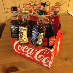 six bottles of coca - cola in a red box on a wooden table