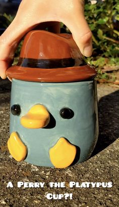 a close up of a person's hand holding a cup with a penguin face on it