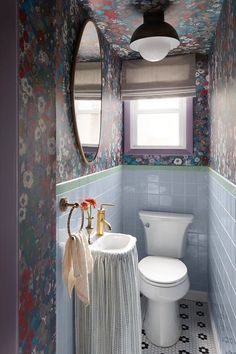 a toilet and sink in a small room with floral wallpaper on the walls above it