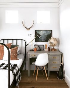 a bedroom with a bed, desk and chair next to a wall mounted deer head