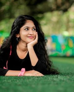 a woman laying on the ground with her hand under her chin and looking at the camera