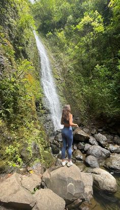 a woman standing in front of a waterfall