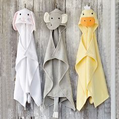 three hooded towels hanging on a wooden wall