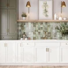 a kitchen with white cabinets and green tile backsplashing on the wall, along with potted plants