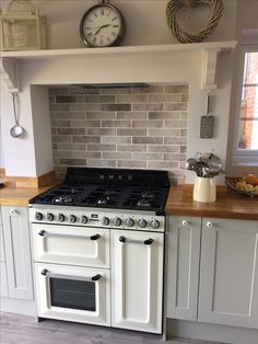 a white stove top oven sitting inside of a kitchen next to a clock on the wall