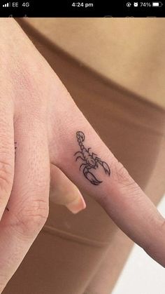 a person's hand with a small scorpion tattoo on the middle finger and fingers