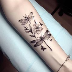 a woman's arm with flowers and dragonflies on it