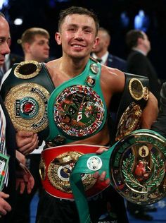 the professional boxer is holding his belts in one hand and smiling at the camera while standing next to him