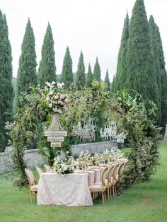 an outdoor table set up with flowers and chandelier in the middle of it