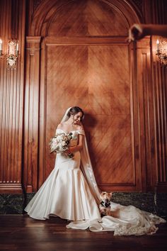 a woman in a wedding dress standing next to a wall with wood paneling on it