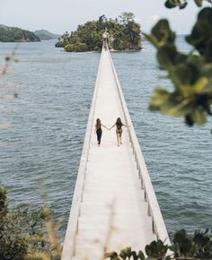 two women walking down a long pier holding hands