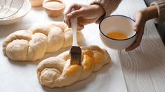 a person is holding a fork and dipping sauce into some bread rolls on a table