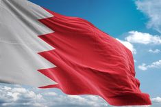 the flag is waving in the wind on a sunny day with blue sky and white clouds